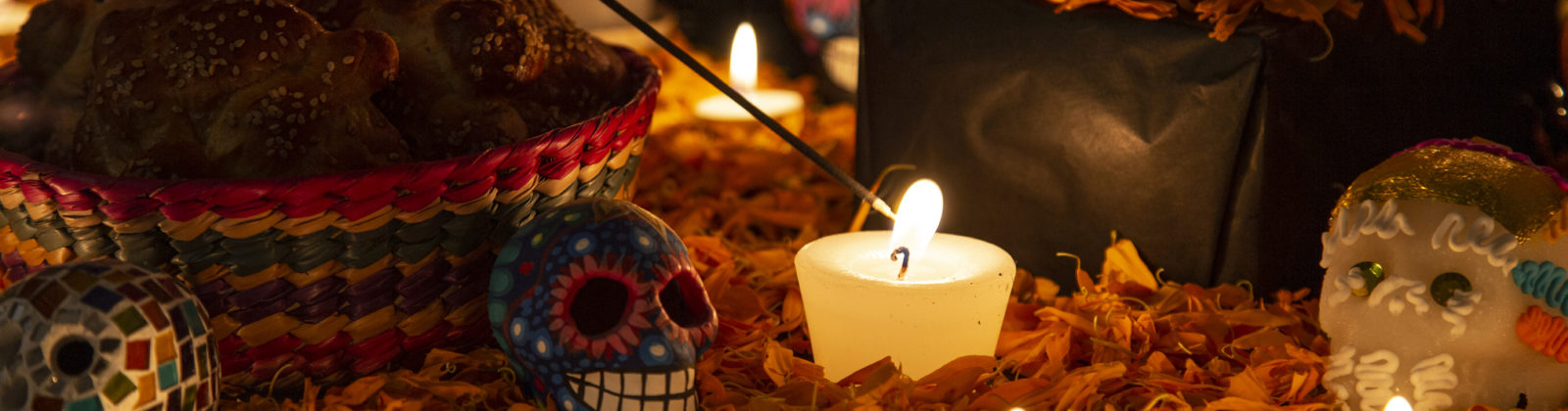 Hand holding incense stick over "ofrenda" for the Day of the Dead in Puebla, Pue., Mexico