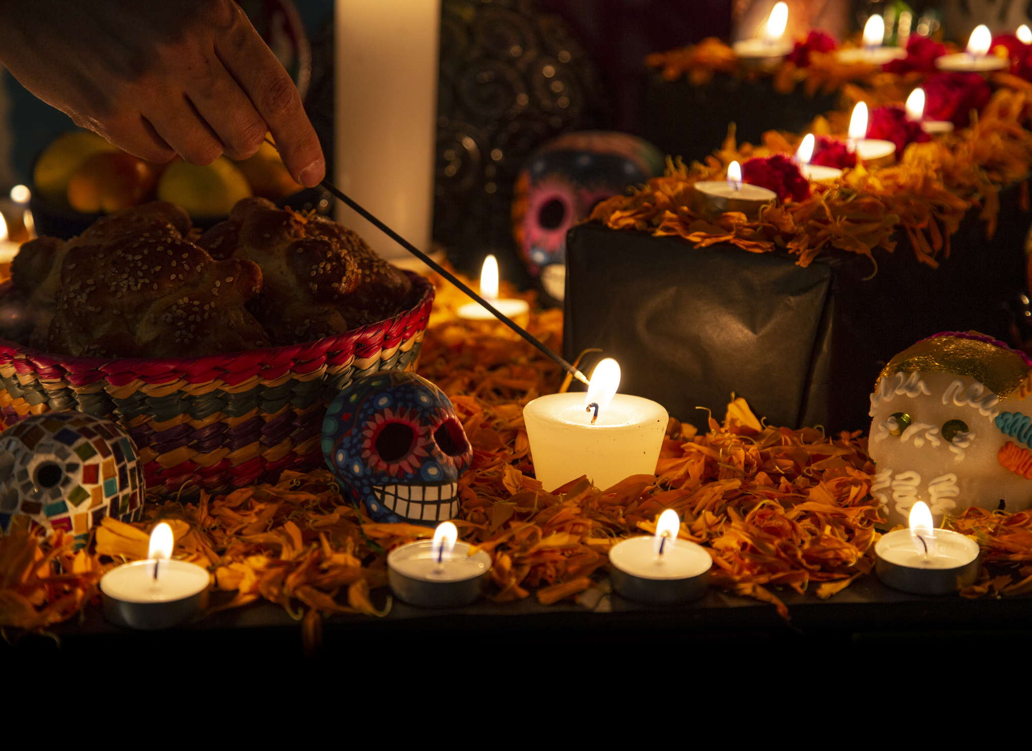 Hand holding incense stick over "ofrenda" for the Day of the Dead in Puebla, Pue., Mexico