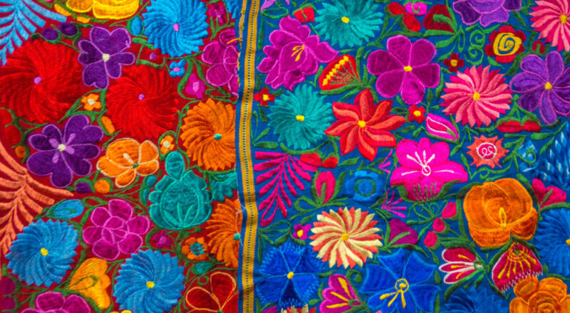 decorative embroidered fabric with bright blue, magenta, green, yellow, and red.